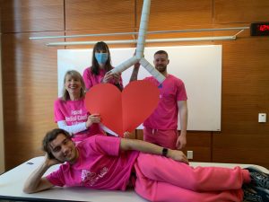 Halloween costumes featuring people wearing pink shirts and holding a paper heart. 