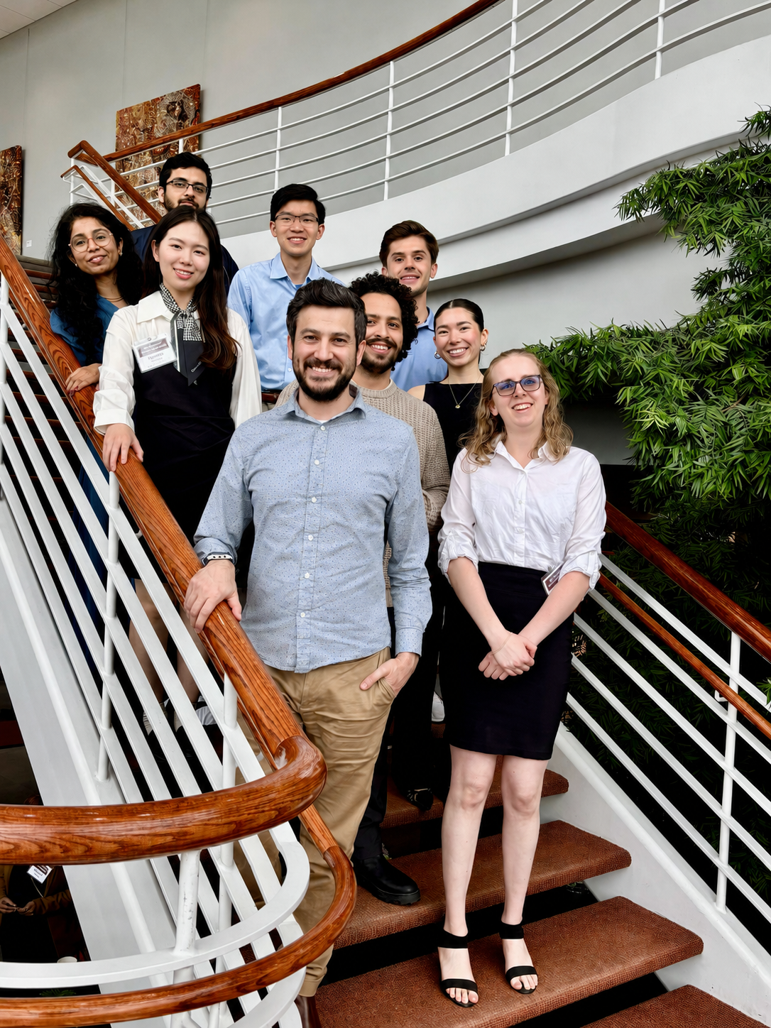 Professor and group of students posing on staircase for photo.